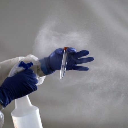A laboratory worker cleans the tube containing a sample from a customer at the Certus Lab's COVID-19 drive-thru test centre at the parking lot of the Caliente multipurpose complex in Tijuana, Baja California State, Mexico, on July 21, 2020 amid the novel coronavirus pandemic. - As Mexico's public health COVID-19 testing rate is one of the lowest worldwide, private laboratories running certified testing have become an option for people that can afford it. (Photo by Guillermo ARIAS / AFP)