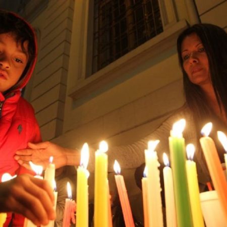 Un niño enciende velas durante la "Noche de las velitas". (EFE)