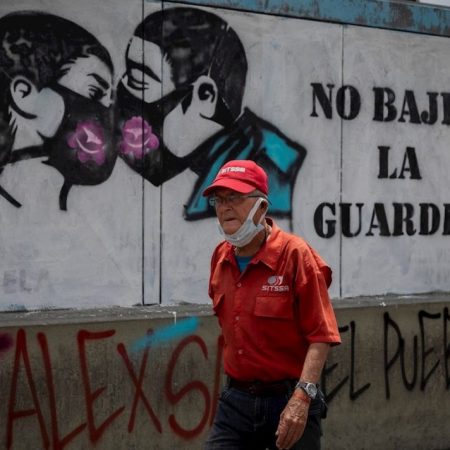 Un hombre camina hoy sin tapabocas frente a un grafiti que invita a su correcto uso para evitar la propagación del covid-19, en Caracas (Venezuela). EFE