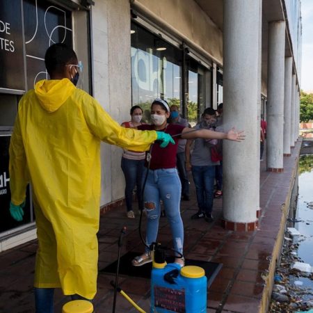 Fotografía del pasado 8 de junio que muestra a un trabajador sanitario desinfectar a un grupo de personas antes de entrar a un local comercial, en Maracaibo (Venezuela). EFE