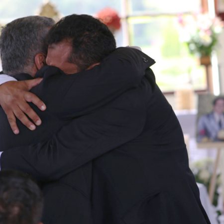 Fotografía cedida por la Unidad de Búsqueda de Personas dadas por Desaparecidas que muestra a familiares de Carmenza Castañeda de Angulo mientras se abrazan en la ceremonia de entrega de sus restos.