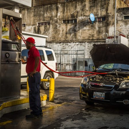 Trabajador de la estación Michelena surte gas a un vehículo. Fotografía: Armando Díaz.