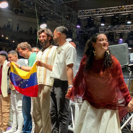 El grupo Hakuna Group Music cierra su concierto en Valencia sosteniendo la bandera de Venezuela y de la mano de todo el equipo. Fotografía: Armando Díaz.