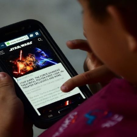 Un niño lee en un teléfono móvil sobre la película "La guerra de las galaxias. El despertar de la fuerza", el 20 de octubre de 2019 en Los Ángeles. AFP